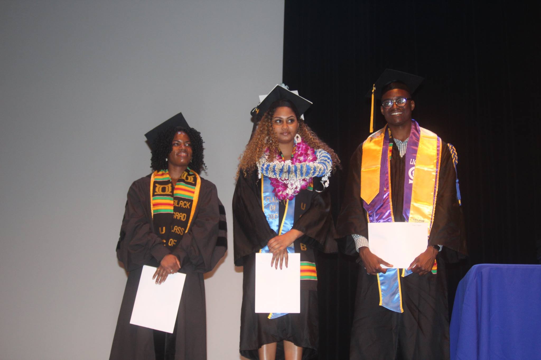 Photo of three students in fraduation caps and gowns