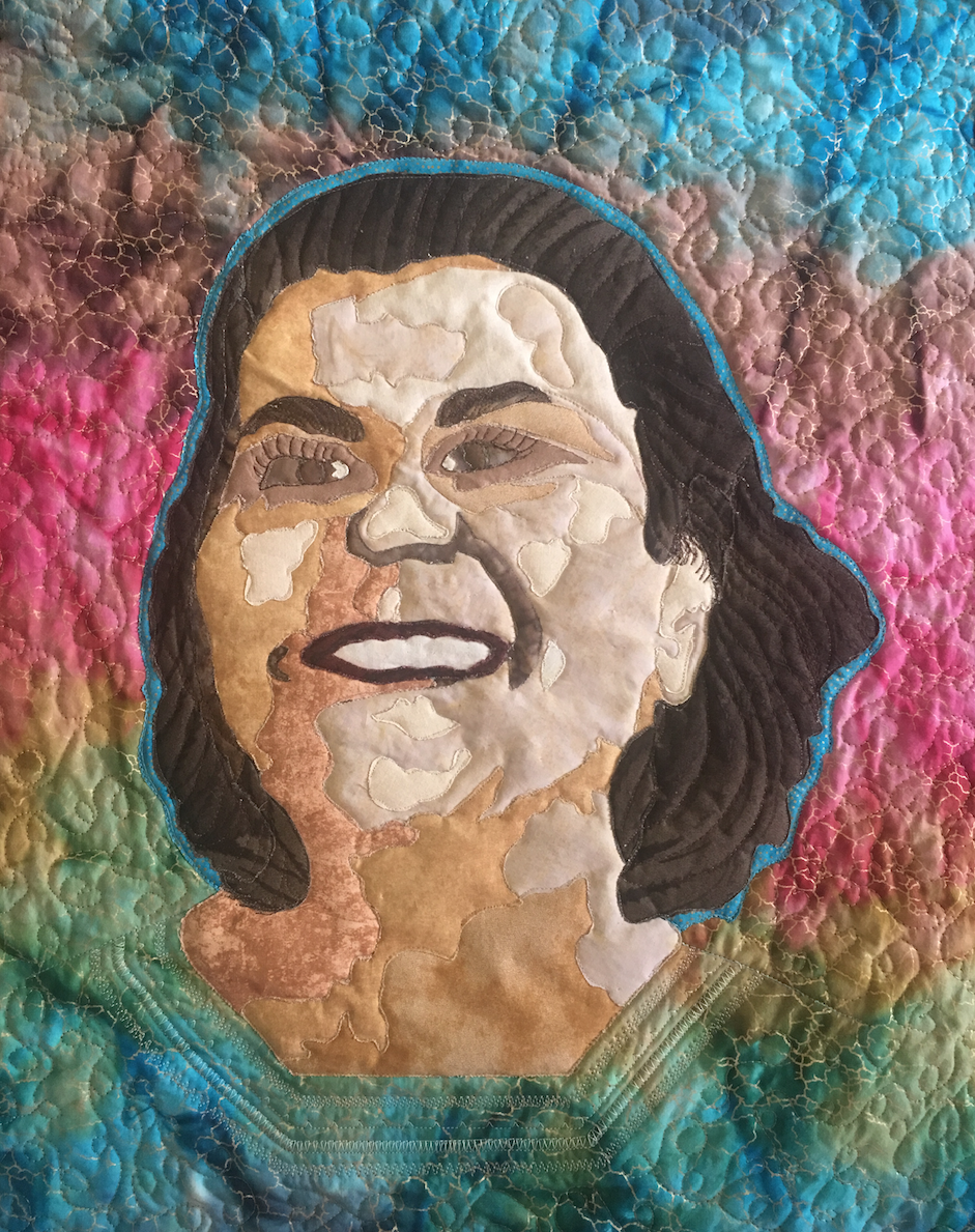 Quilt featuring the face of Claudine Michel with a rainbow background 