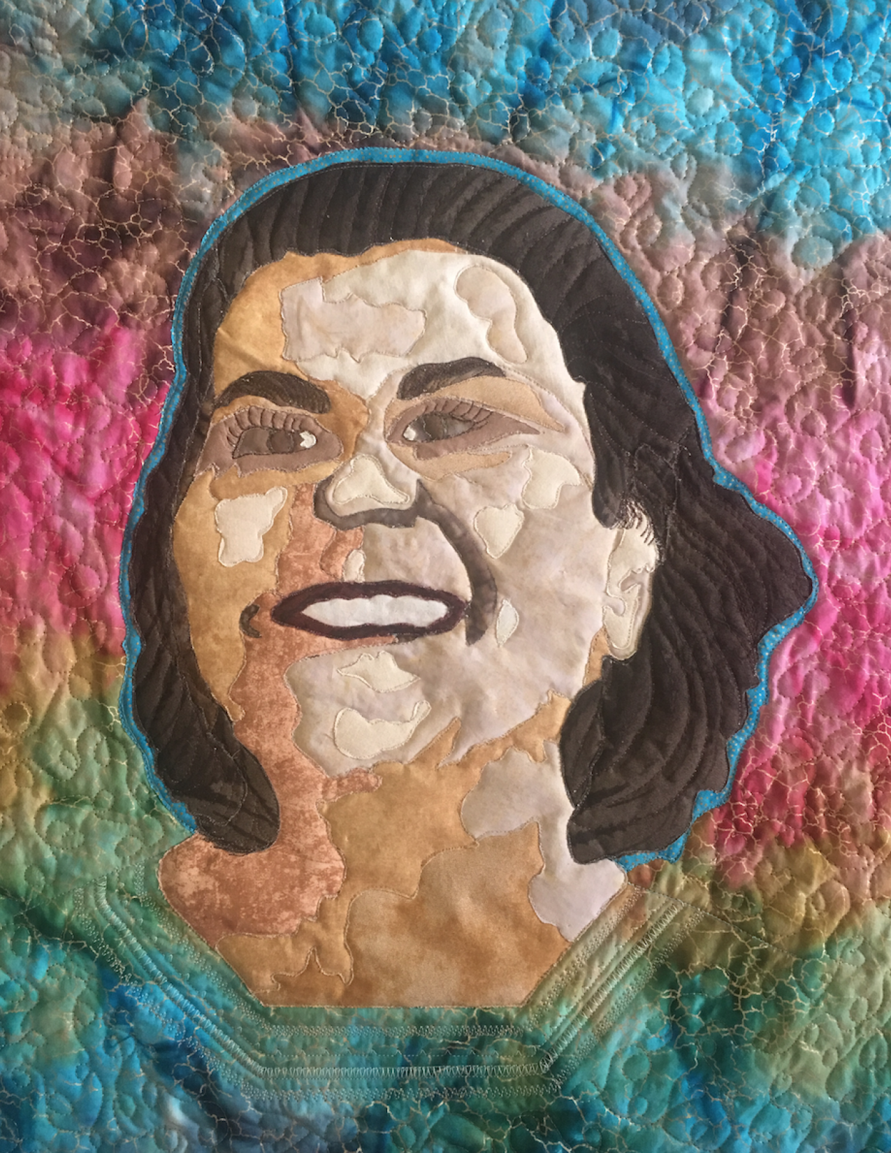 Quilt featuring the face of Claudine Michel with a rainbow background 